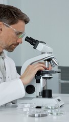 Scientist conducting focused research using a laboratory microscope, manipulating controls while...