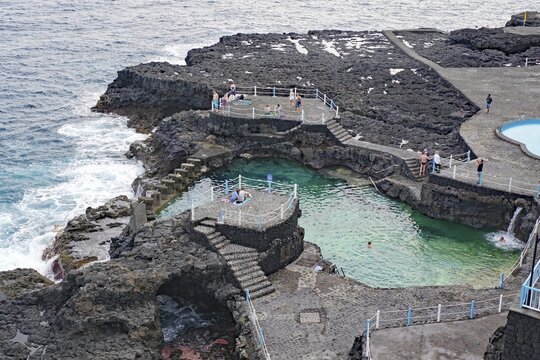 Rocky coastline with natural pools and people enjoying the waves by the sea, Charco Azul, Los Sauces, La Palma, Canary Islands, Spain