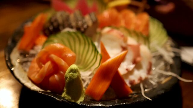 Close up of delicious sashimi platter with salmon and octopus served with wasabi and cucumber.