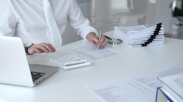 Accountant calculating tax, reviewing financial report, and managing business paperwork on a modern office desk, processing data for audit and budget planning. Audit and taxes