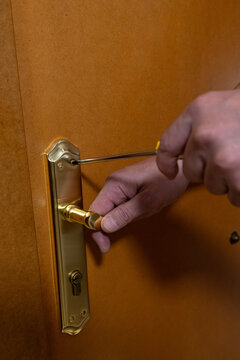 Hand repairing door handle with screwdriver doing diy home maintenance