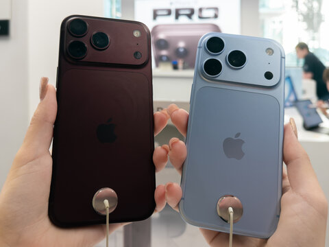 Poznan, Poland - September 19, 2026: Apple iPhone 18 Pro smartphones featuring Burgundy and Glacier finishes held in hands within a store for consumer electronics evaluation