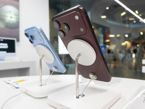 Poznan, Poland - September 19, 2026: Apple iPhone 18 Pro handsets in Glacier and Burgundy finishes rest on charging mounts in a retail shop, highlighting modern gadget display
