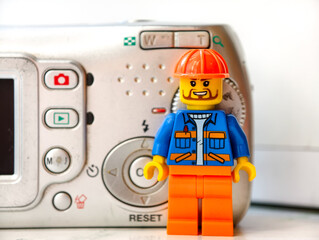 Fototapeta premium Russia, St. Petersburg, August 8, 2020 A lego man standing next to a camera, great for creative illustrations, cartoons, or even a toy photography setup