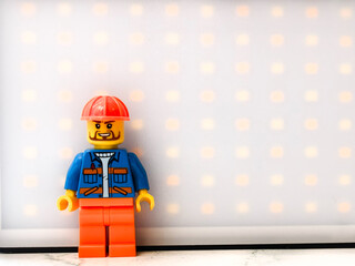 Fototapeta premium Russia, St. Petersburg, August 8, 2020 A close-up of a Lego man wearing a hard hat, great for illustration or construction-themed designs