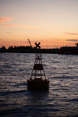 Navigation buoy at sunset with boats on the water © LuongTu