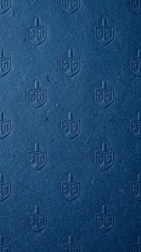 Embossed blue handmade paper texture featuring traditional Jewish dreidel pattern for Hanukkah holiday celebration background concept