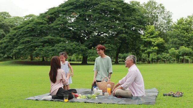 Slow motion hugging Happy mother and daughter, Happy Asian family having fun time on picnic at city nature park sunny day, outdoor activitie with daughter father, mother and grandfather