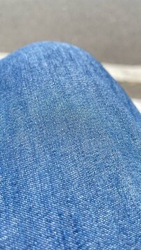 Detailed macro photograph showcasing the woven texture, pattern, and rich blue color of denim fabric from a pair of jeans, featuring a soft-focused background