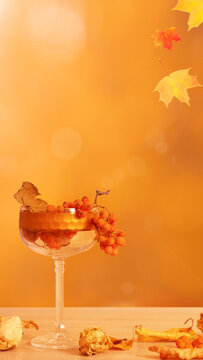 Autumn composition with a wine glass, rowan berries, and fallen leaves