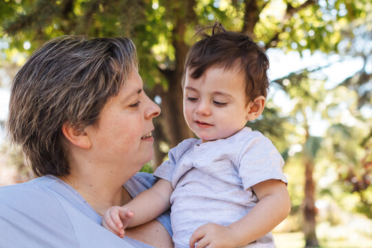 Mother holding toddler son smiling outdoors