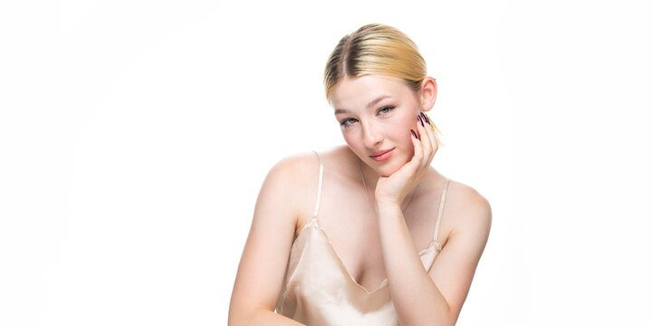 A young blonde girl with freckles in a golden top. Beauty portrait of a woman on a white background in the studio.