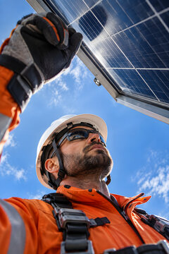 Unusual upward portrait emphasizing solar safety equipment and worker expression.