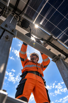 Solar technician silhouetted through photovoltaic structures with a sunburst.