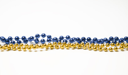 Minimalist holiday composition of shiny blue and gold bead garlands lying on a white background with wide copy space perfect for Christmas greetings © Tetiana