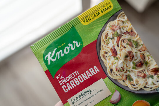 Warsaw, Poland - Sep 20, 2026: Knorr Fix Spaghetti Carbonara sachet with a photo of the prepared dish held in a hand against a blurred light background indoors