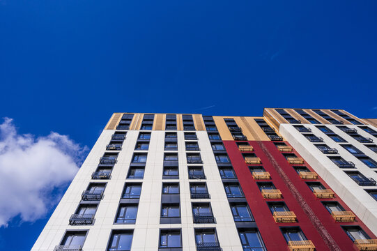 The exterior of a modern multi-storey residential building - facade, windows and balconies against the sky