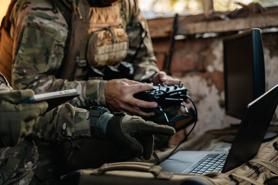 Soldier operates a drone control console. Military personnel is carrying out a combat mission at a position in an abandoned house.
