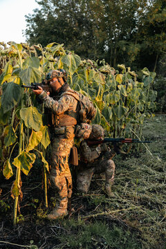Military Soldiers with assault rifles at a combat position in a field. Military personnel carrying out a combat mission.