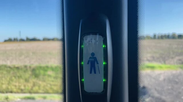 A digital display located at a bus stop shows a symbol that represents a person using a cane, clearly denoting accessibility features
