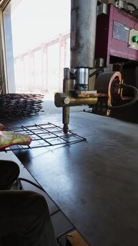 Spot welding machine joining a steel reinforcement mesh on a workbench at a factory