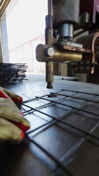 Spot welding electrode pressing down on a steel reinforcement mesh at a factory