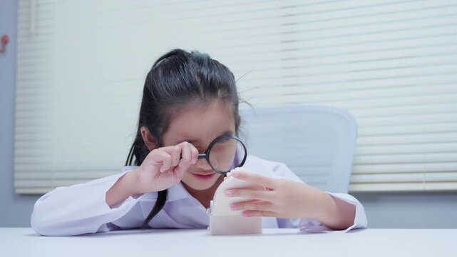 Young student dentist girl using magnifying glass examining plastic teeth model in clinic for oral hygiene education
