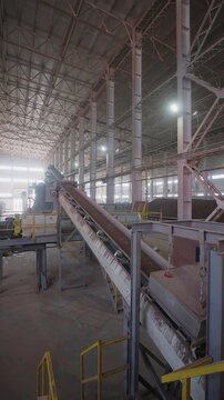 Belt conveyor carrying red clay through a large hall at a brick factory