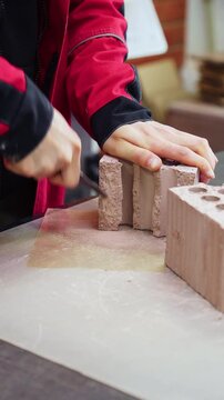 Laboratory worker scraping a clay brick sample with a steel tool at a brick factory