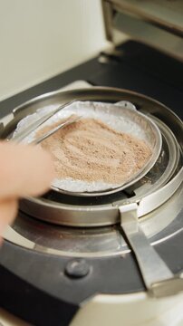 Tweezers spreading a clay powder sample in a laboratory moisture analyzer
