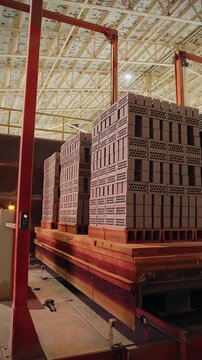 Kiln cars loaded with stacked bricks inside a tunnel kiln hall at a brick factory