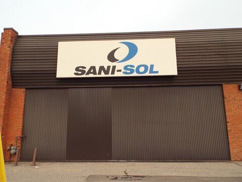 Ottawa, Ontario, Canada &ndash; July 17, 2026: : A large rectangular sign reading "SANI-SOL" with a blue and black abstract logo mounted on a dark ribbed industrial building facade on Canotek Rd.