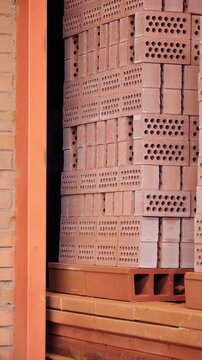 Stacked red clay bricks at the entrance of a tunnel kiln at a brick factory