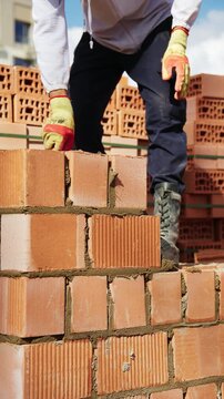 Bricklayer spreading mortar with a trowel while building a brick wall outdoors