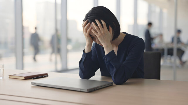 Japanese woman looking stressed while sitting indoors