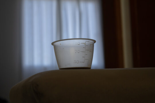 Small plastic measuring cup with liquid and scale markings on a surface indoors