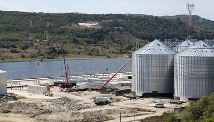 Grain silos construction site by river port © Lovec1
