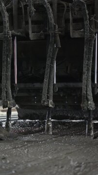 Worker with a shovel under a row of concrete vibrators above a freshly poured slab
