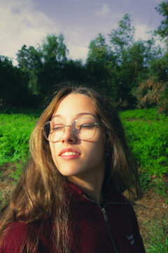 Retrato de joven con gafas sonriendo bajo la luz dorada del atardecer al aire libre