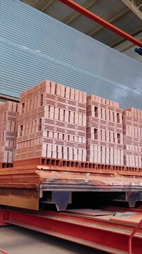 Kiln car loaded with stacked clay bricks under a canopy at a brick factory