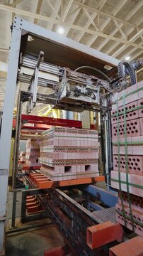 Automated machine strapping packs of clay bricks on a line at a brick factory