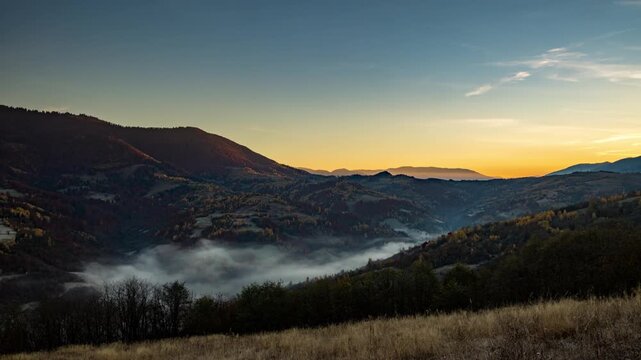 Sun rises in highland and morning fog fills valley in autumn