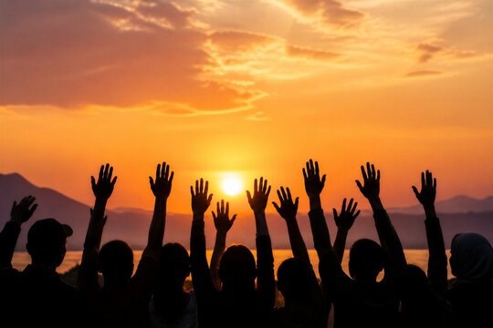 Group raising hands toward sunset over lake shore horizon