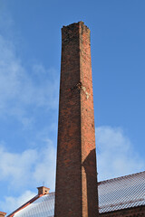 Fototapeta premium Square brick chimney from an old abandoned factory against blue sky
