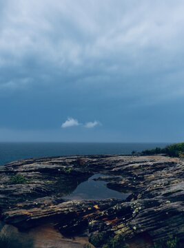Rocky coastal landscape with tidal pool under a cloudy blue sky 