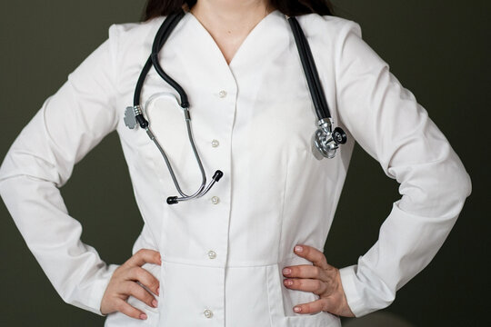 Cropped view of a female medical practitioner or nurse wearing a white lab coat and black stethoscope around her neck