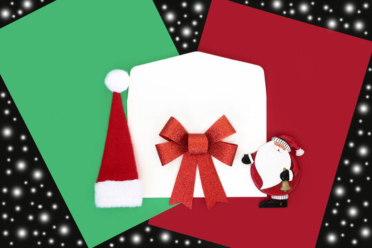 Christmas mail art, white envelope and vintage santa ornament, hat and bow decorations with red green letter paper, abstract snow on black.