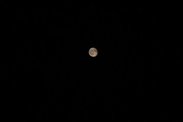 A full moon glowing against a deep black night sky, with a few faint stars scattered around it. © Inna Trokhymets 
