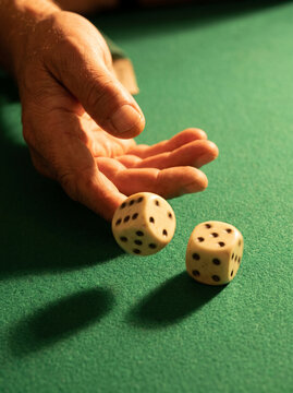 Hand throwing two dice on a green felt surface  
