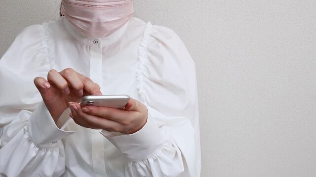 マスクをした女性　咳やくしゃみをしながらスマートフォンを操作する様子